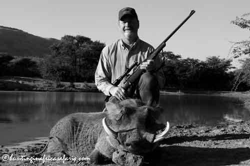 Trophy warthog hutning South Africa by war veteran Afghanistan War Veteran Dwayne, an adapted hunter with a walking impairment, celebrates his successful hunt next to a trophy warthog (Phacochoerus africanus) in South Africa, taken from an improvised blind at a waterhole.