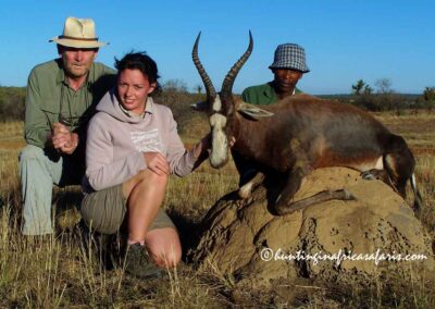 A father and daughter posing with a Blesbok Damaliscus pygargus phillipsi on a termite mound in Gauteng.