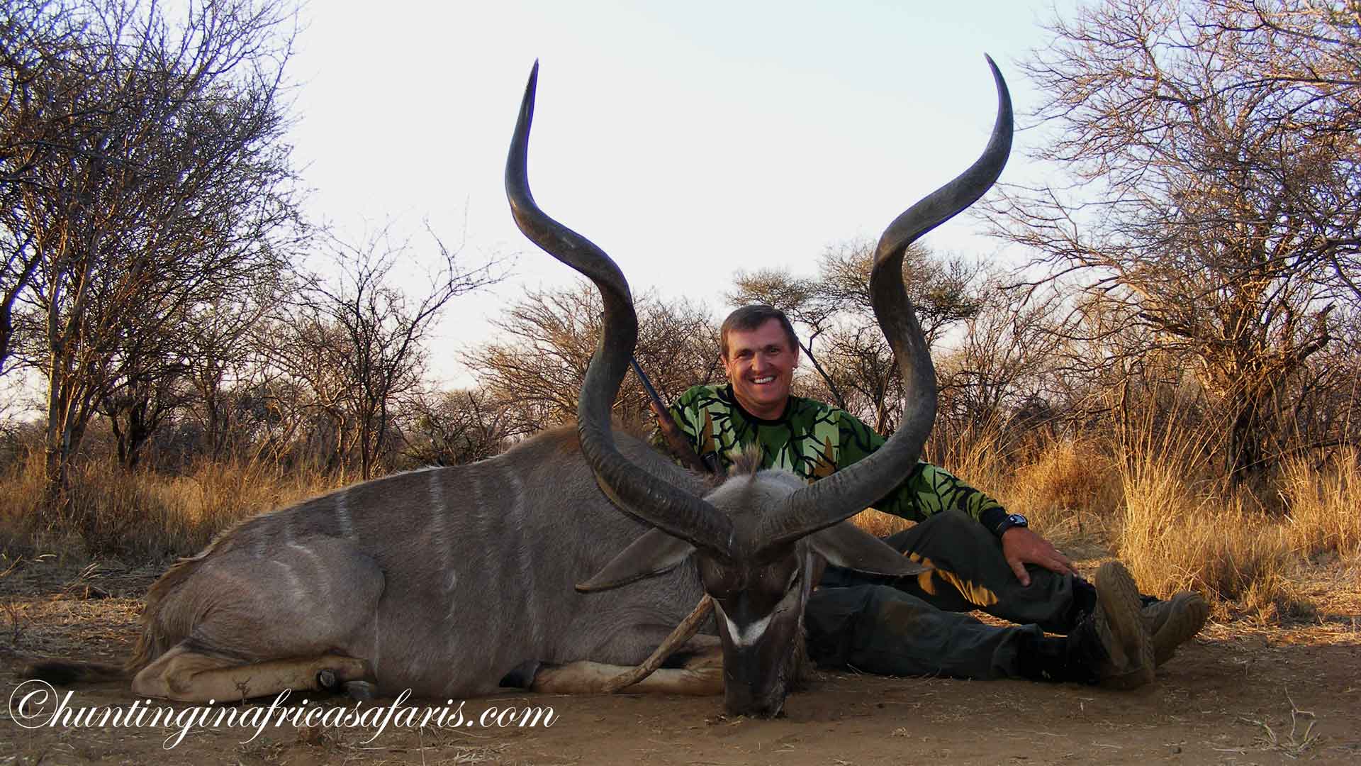 Smiling couple (husband and wife) posing with an impressive 52-inch wide Kudu bull trophy (Tragelaphus strepsiceros) in South Africa's North West Province.